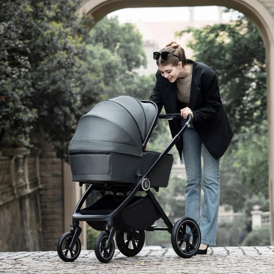 Woman pushing a gray and black stroller outdoors.