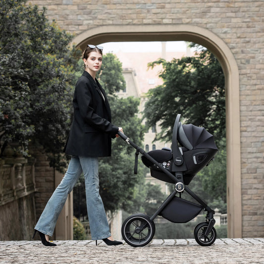 Woman pushing a black stroller in an outdoor setting with a stone archway and greenery.