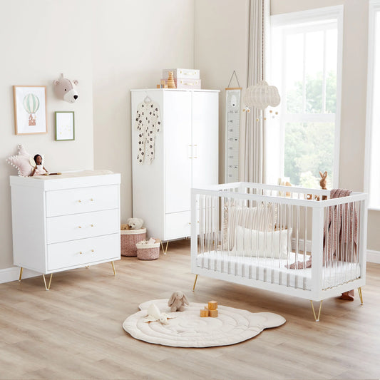 Nursery room with white crib, dresser, and wardrobe.