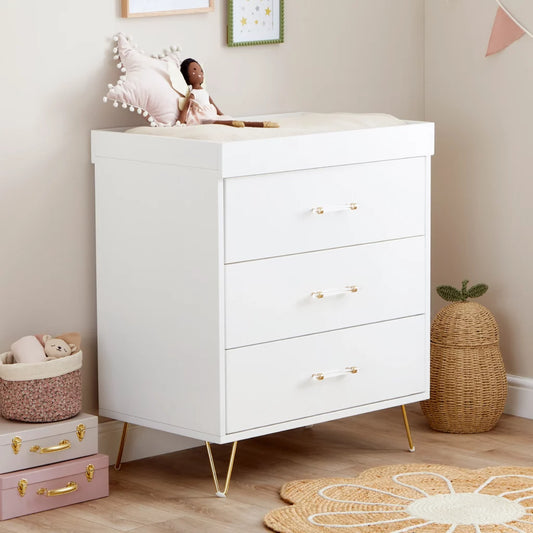 White dresser with gold legs and handles in a child's room