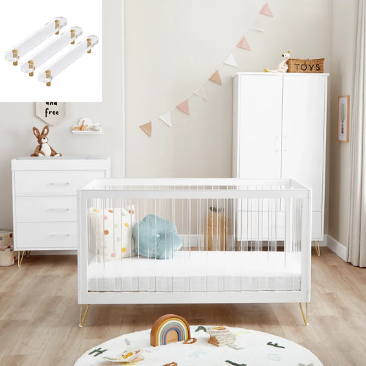 Nursery room with white crib, dresser, and toys on a wooden floor.