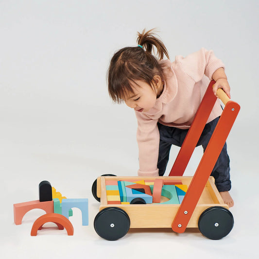 Child playing with a wooden toy cart on a white background