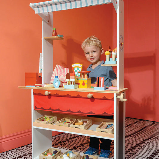 Child playing with a toy kitchen set against an orange wall