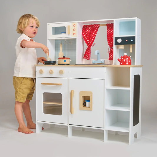 Child playing with a toy kitchen set on a plain background