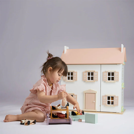 Child playing with a dollhouse and accessories on a plain background