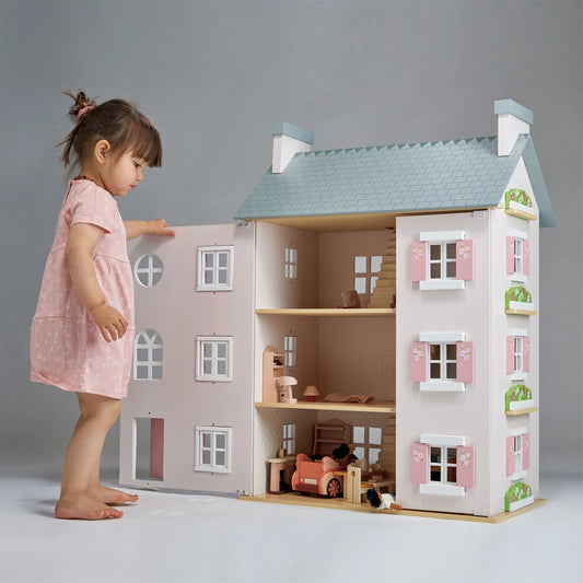 Child playing with a dollhouse on a gray background