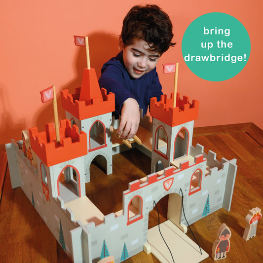 Child playing with a toy castle set against an orange wall.