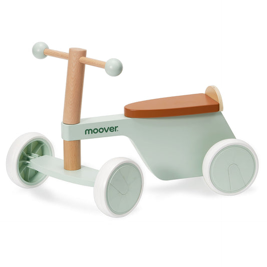 Children's balance bike with wooden handlebar and seat, green body, and white wheels on a white background.