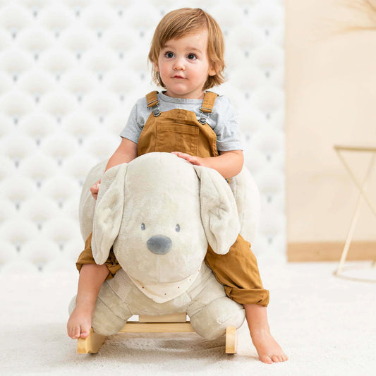 Child sitting on a rocking horse in a room with padded walls.