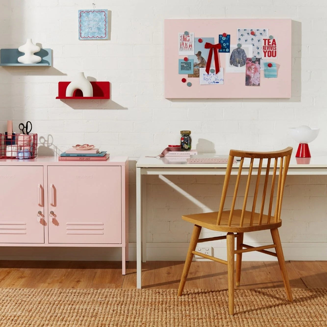 Home office with pink storage unit, wooden chair, and decorative items.