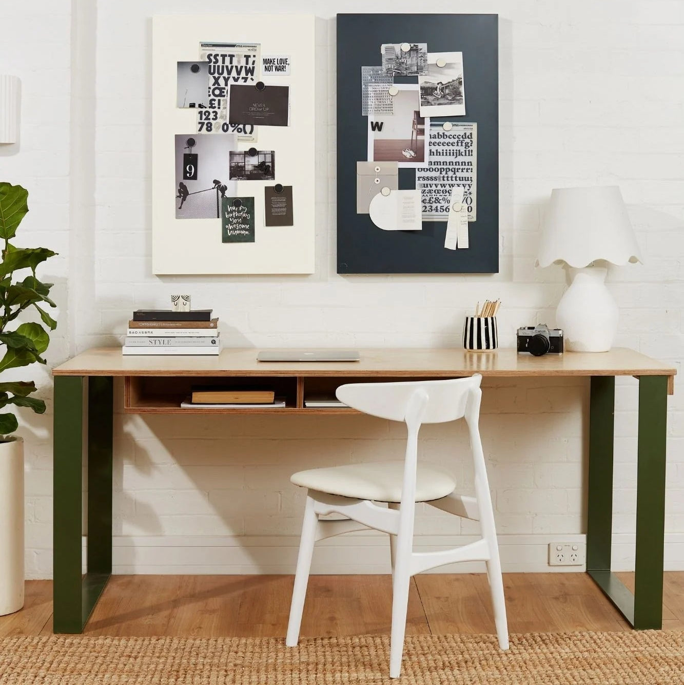 Modern desk with a chair, books, and decorative items against a white wall.