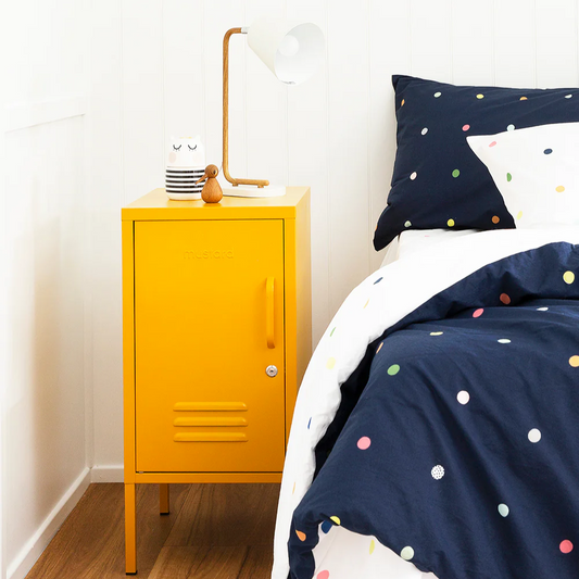 Yellow locker-style nightstand next to a bed with polka dot bedding.