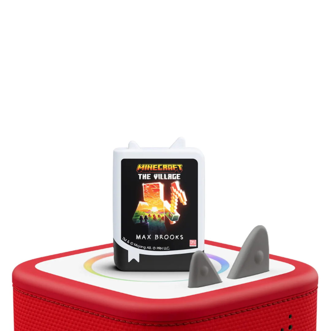 Red electronic device with a book titled 'The Village' by Max Brooks on top