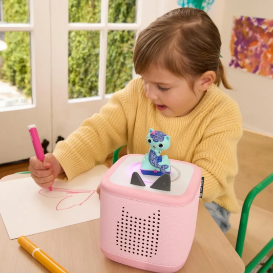 Child playing with a pink toy on a table in a classroom setting