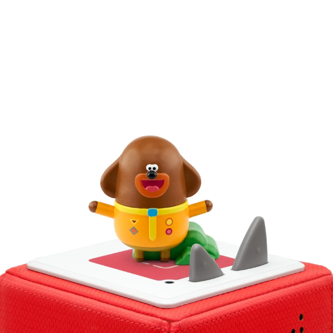 Toy figure of a brown dog with a yellow sweater on a red and white base