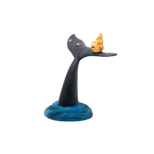 Toy figure of a whale with a small boat on its back on a white background