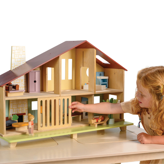 Wooden dollhouse with furniture and toys on a white background