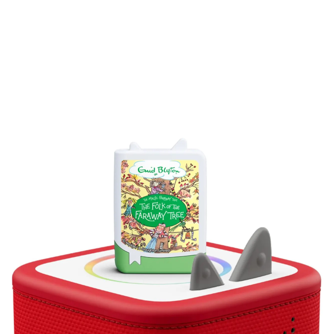 Children's book titled 'The Folk of the Faraway Tree' on a red and white surface with a toy shark.