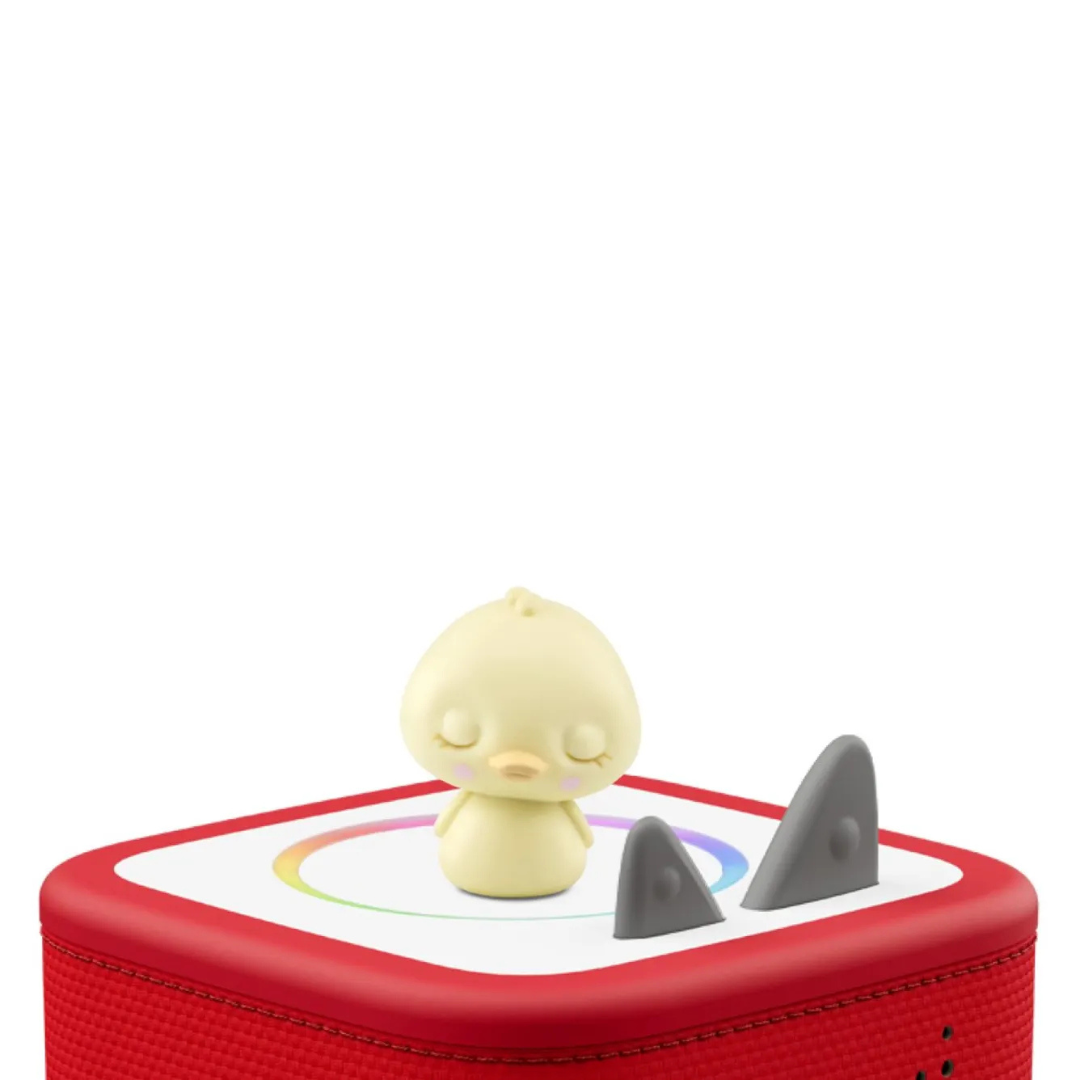 Small yellow duck toy with shark fins on a red and white base against a white background