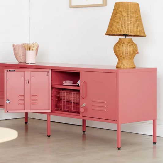 Pink cabinet with a lamp and ice cream-themed poster in a room.