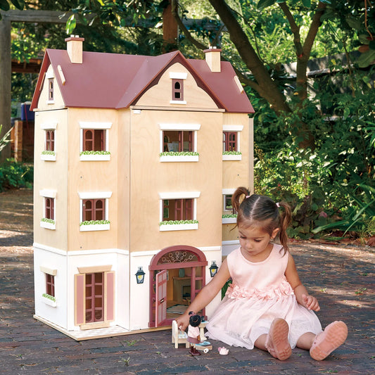 Child playing with a toy dollhouse outdoors