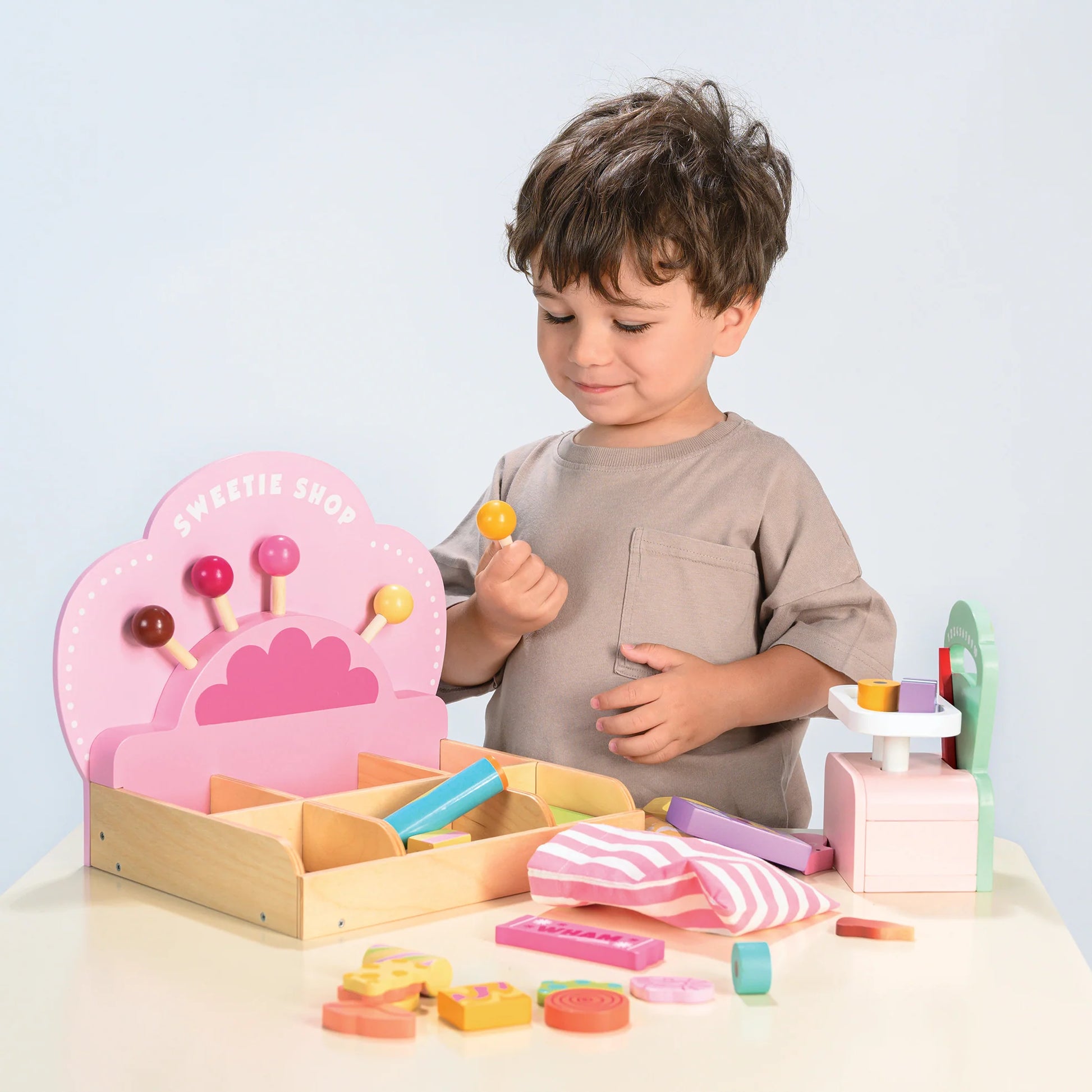 Child playing with a wooden toy set on a light blue background