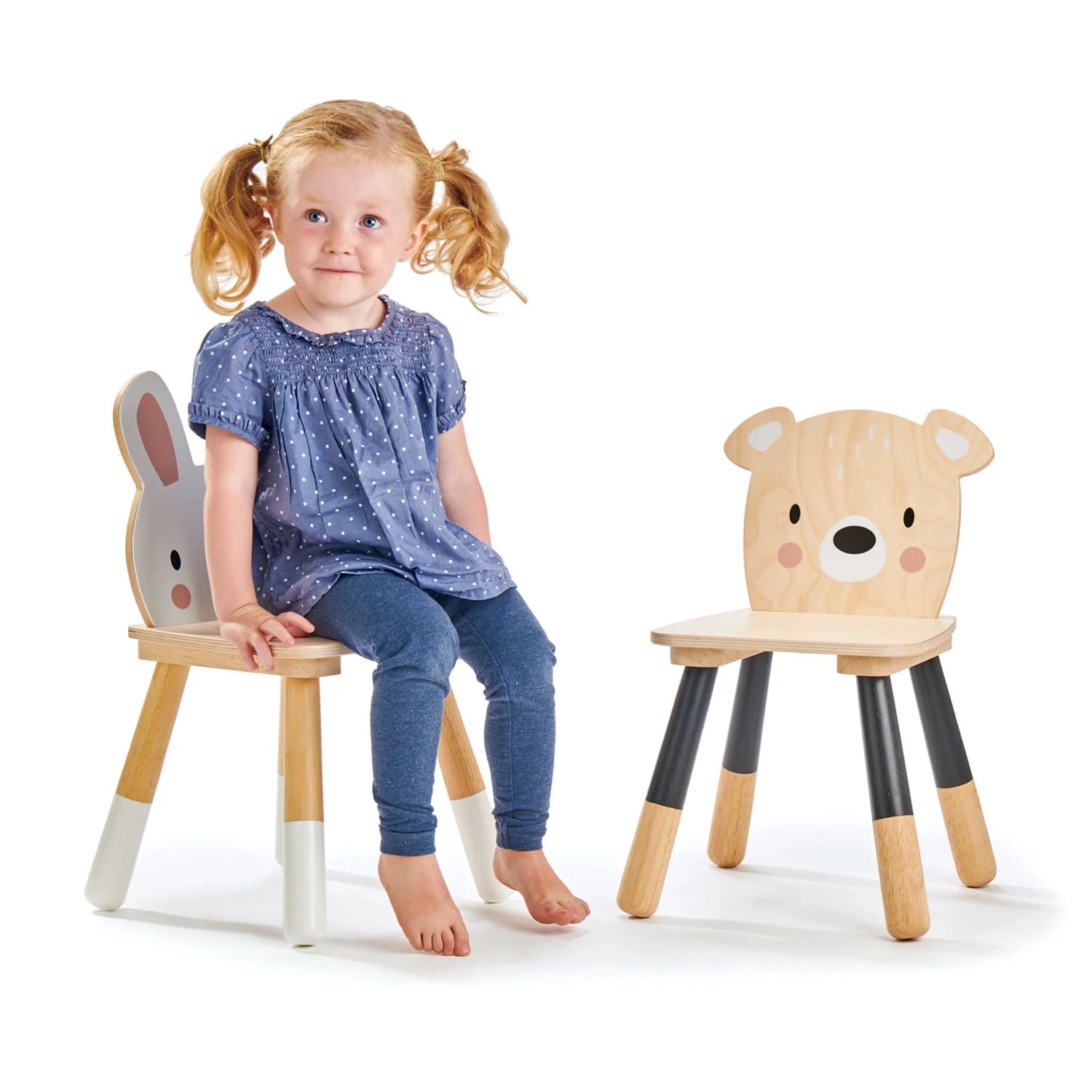 Child sitting on a wooden chair with animal face design, next to another similar chair.