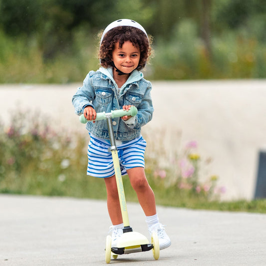 Child riding a scooter outdoors with a blurred natural background