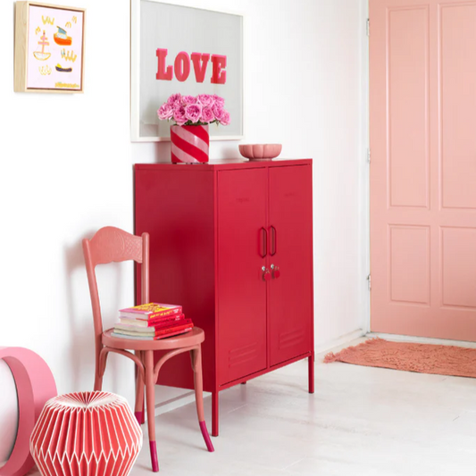 Modern interior with a red cabinet, pink chair, and decorative elements.