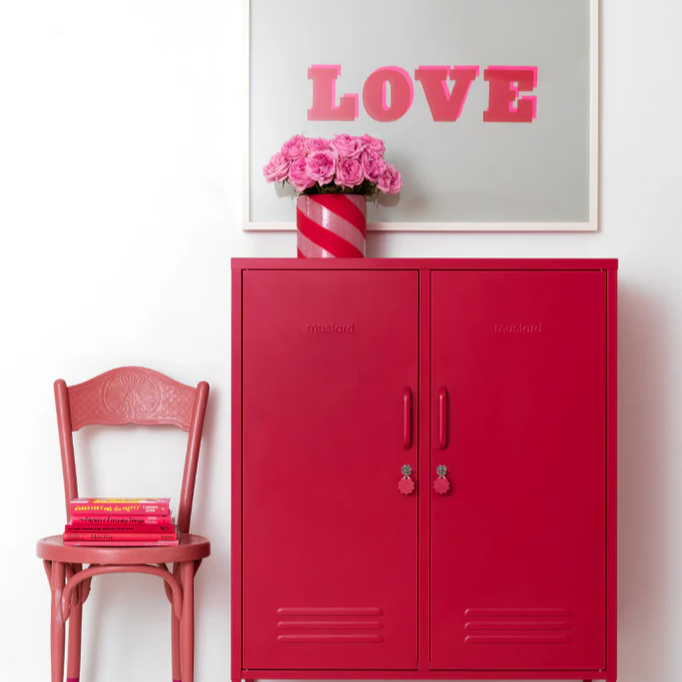 Red cabinet with a pink chair and 'LOVE' artwork on a white wall