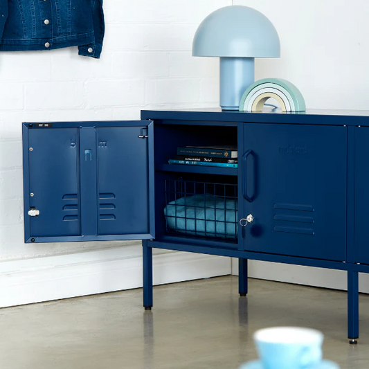 Blue locker-style cabinet with open door, denim jacket on wall, and books on surface.