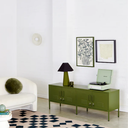 Modern living room with a green console table, white armchair, and geometric rug.