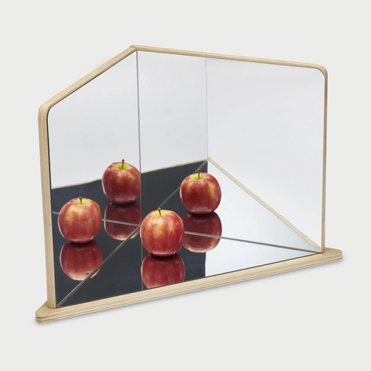 Geometric mirror with a wooden frame displaying four red apples on a reflective surface.