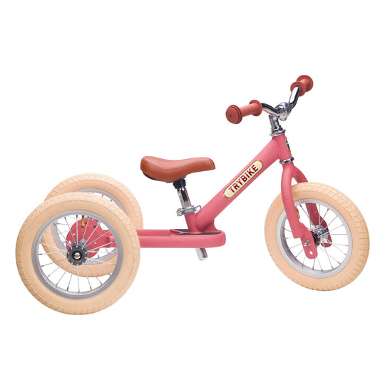 Pink balance bike with tan wheels on a white background