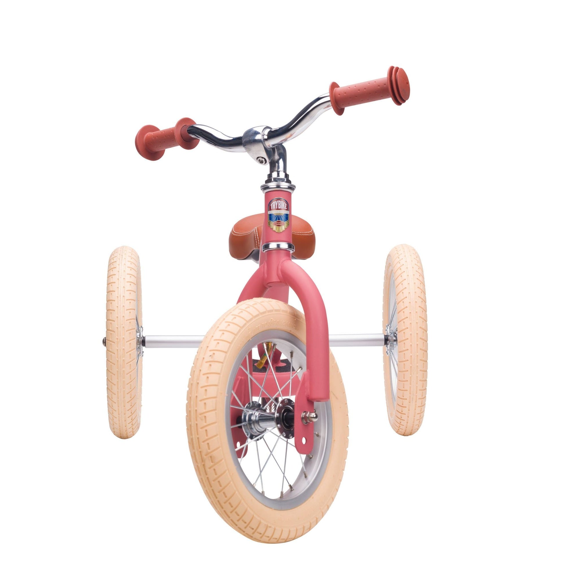 Pink balance bike with tan wheels on a white background