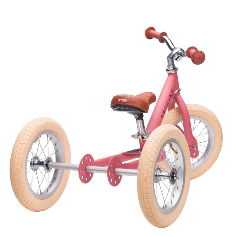 Pink balance bike with tan wheels on a white background