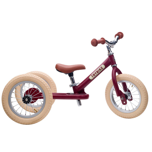 Red balance bike with beige tires on a white background