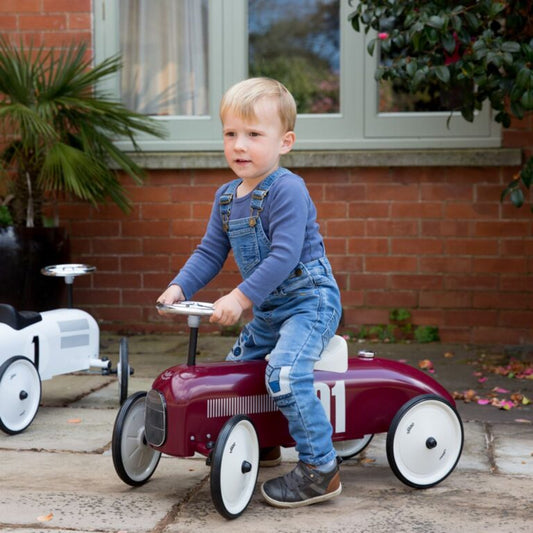 Burgundy ride on toy car with child riding on it
