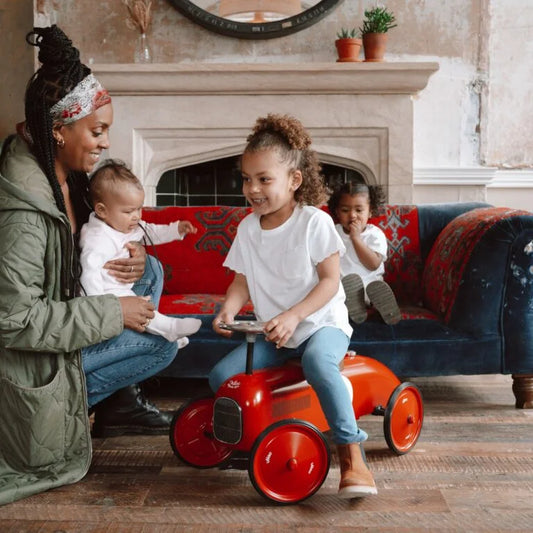 Woman with two children in a living room with a red toy car