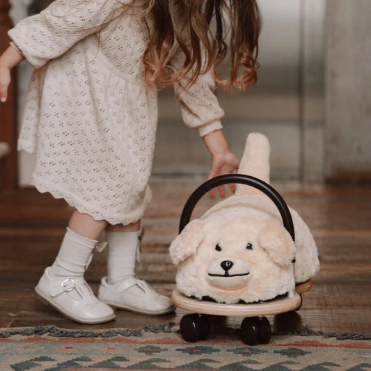 Child stood next to plush dog ride on toy