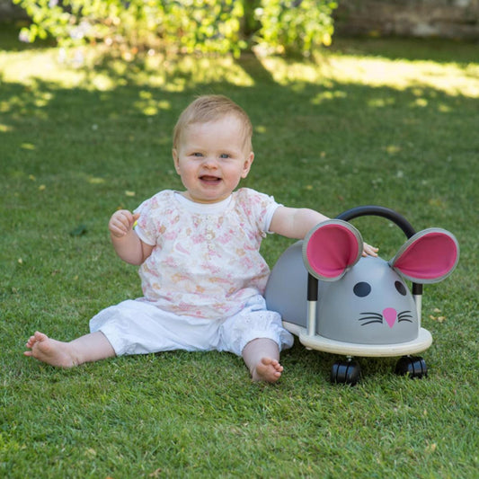 Child sat outside next to mouse ride on toy