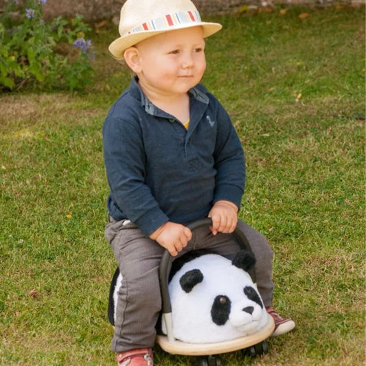 Child sitting on a panda-shaped toy in a grassy area