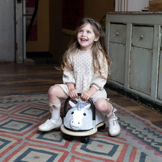 Young girl sitting on a toy horse indoors