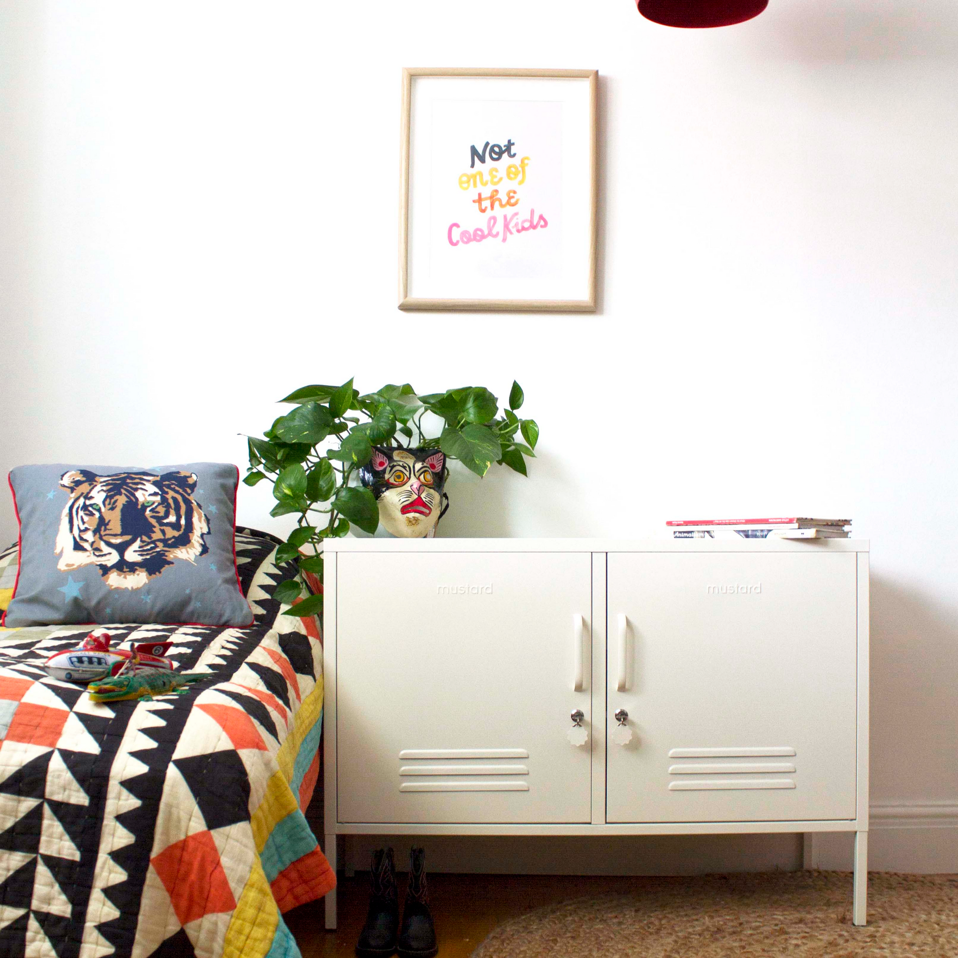 Room interior with a white cabinet, colorful blanket, and framed picture on a white wall.