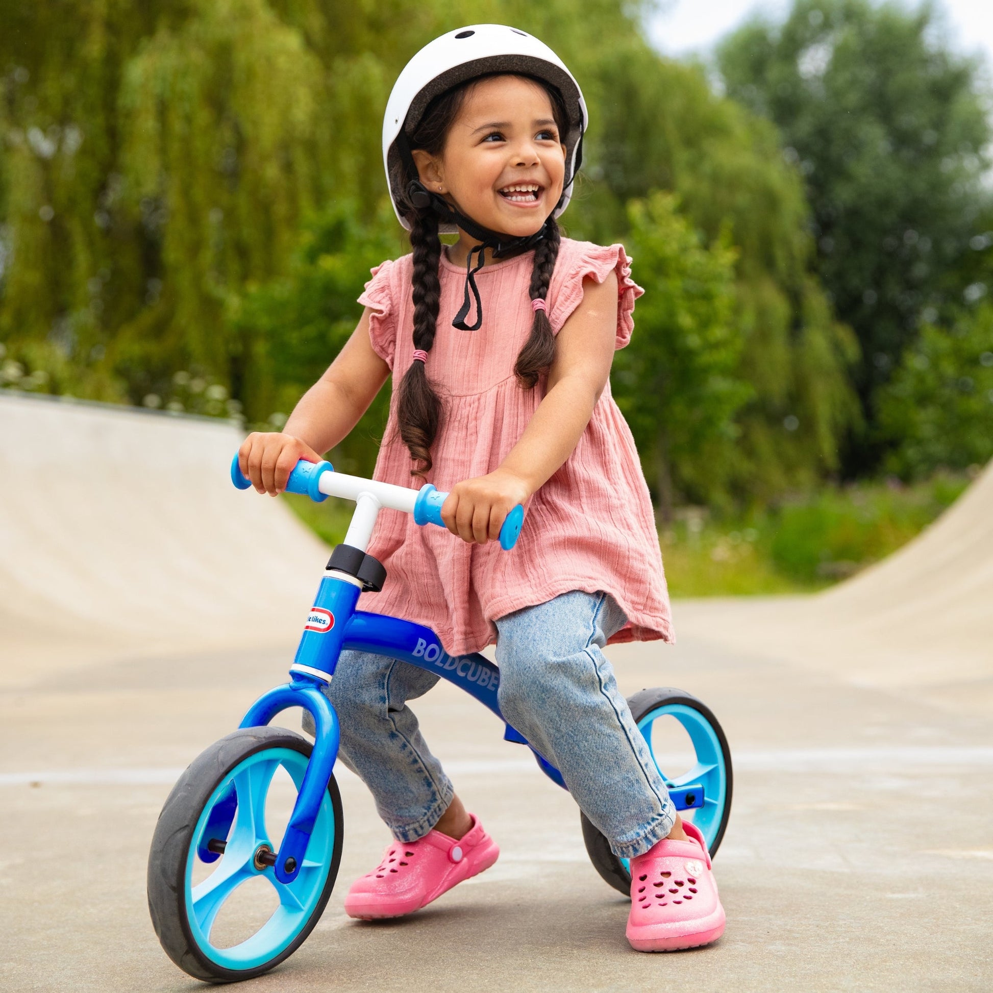 Child riding a balance bike outdoors on a sunny day