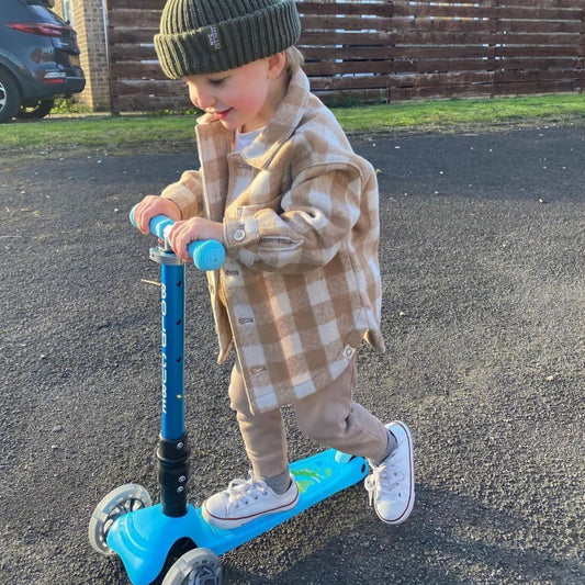 Child riding a blue scooter on a driveway