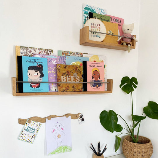 Wooden shelves with books and a plant on a white wall