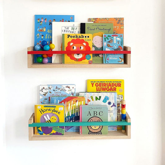 Children's books on a wooden shelf against a white wall