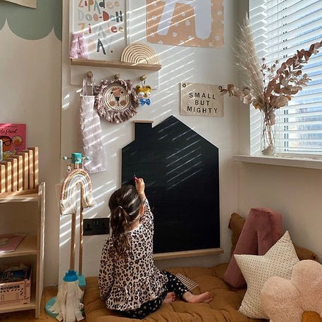 Child playing with a blackboard in a child-friendly room with educational decor.