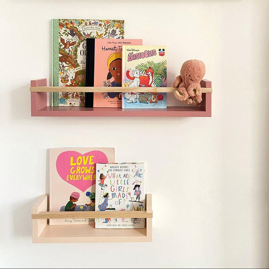Children's books and toys on wooden shelves against a white wall